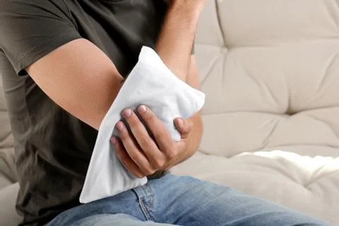 Man using heating pad on sofa, closeup. Space for text 스톡 사진