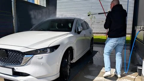 Man Using High Pressure Water Jet to Wash White Modern SUV Fotos de archivo