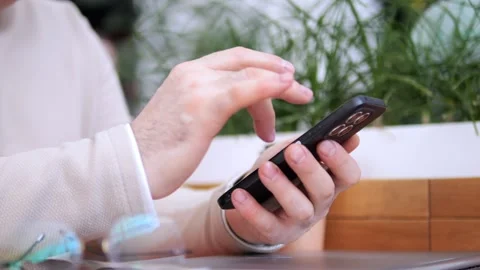 Man is using his cell phone while sitting at a table Stock Footage 307498455