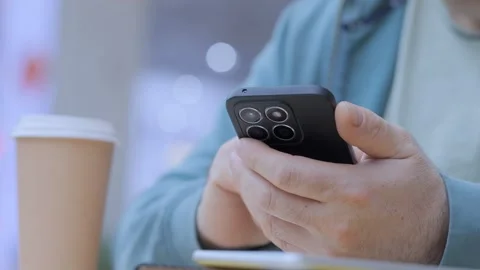 Man is using his cell phone while sitting at a table with a cup of coffee Stock Footage 310224595