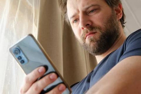 Man using his cellphone. Handsome guy use mobile phone at home. Male browses Stock Photos
