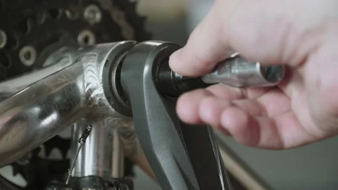 Man is using his hand to screw metal bicycle crank puller into bicycle crank. Stock Footage 195983504