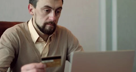 Man using his laptop and a credit card in his office. Stock Footage 86227897