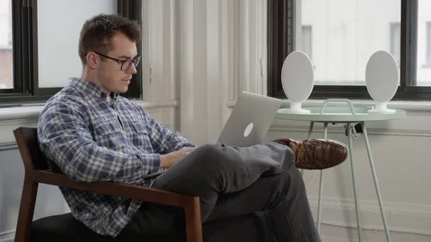 Man using his laptop in a bright spaceous apartment Stock Footage 78733123