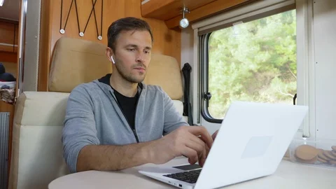 Man using his laptop sitting at a table in the motorhome Stock Footage 122087052