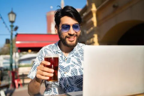Man using his laptop while drinking beer. Stock Photos