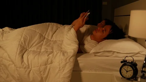 Man using his mobile phone in bed at night Stock Footage 86438411
