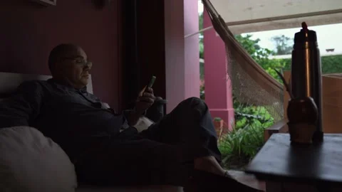 Man using his mobile phone sitting in the gallery of his house Stock Footage 152909097