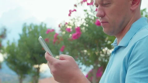A man using his mobile phone outdoors. A man browsing an app on his mobile phone Stock Footage 307791569
