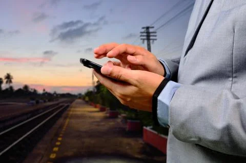 Man using his mobile phone on empty railway platform. Close-up hands Stock Photos