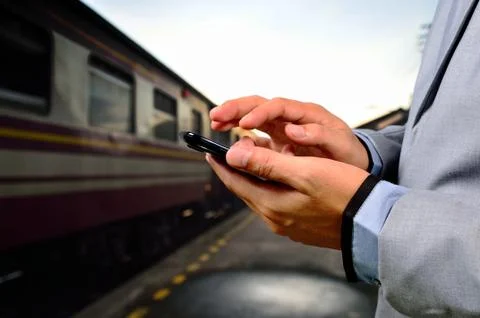 Man using his mobile phone on empty railway platform. Close-up hands Foto stock