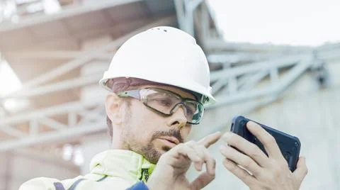 Man using his mobile phone in a factory. Selective focus Stock Photos