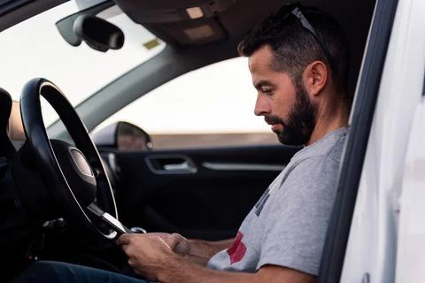 Man using his mobile phone sitting inside his car Stock Photos