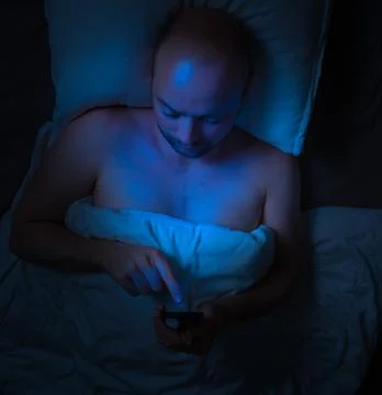 Man using his phone in bed at night . 스톡 사진