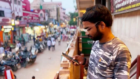 A man using his phone at a bustling Varanasi market Stock Footage 285421930