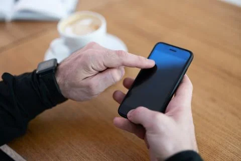 Man using his phone in coffee shop. Smartphone with blank copy space screen. Cup Stock Photos