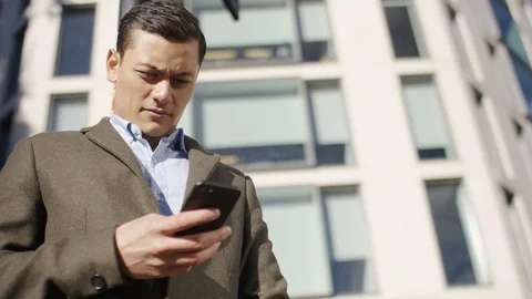 Man using his phone as he waits in the city  Video stock 97974312