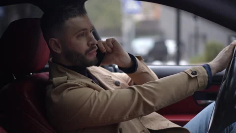 A man using his phone while driving in his car exemplifies a modern urban  Stock Footage 314762604