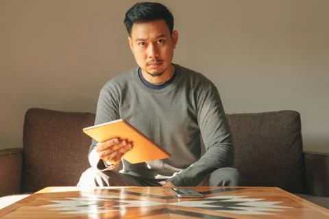 Man is using his smart tablet device in his living room apartment. Stock-Fotos