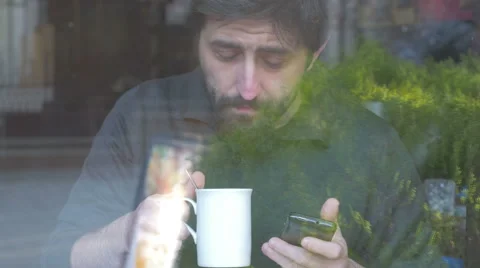 Man using his smartphone and drinking in a coffee shop Stock Footage 48102424