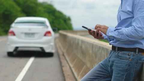 A man is using his smartphone and social media to get help because his car Stock Footage 140669474