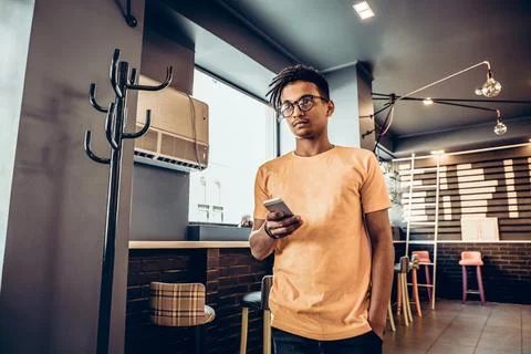 Man using his smartphone in a coffee shop. The concept of study, freelancing, Stock Photos