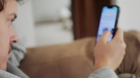 Man using his smartphone at home, scrolling and tapping through... Stock Footage 318177799
