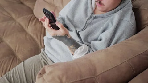 Man using his smartphone at home, scrolling and tapping through... Vidéo 318177863