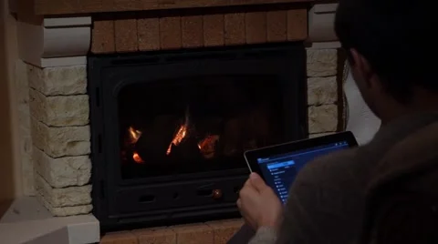 Man Is Using His Tablet In Front Of A Fireplace Technology and Home Concept Stock Footage 44015597