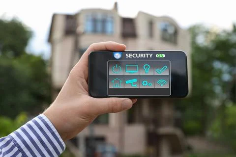 Man using home security application on smartphone in front of house outdoors, Stock Photos