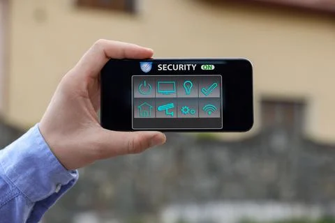 Man using home security application on smartphone in front of house outdoors, Stock Photos