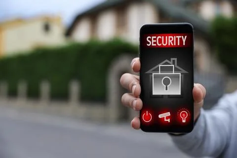 Man using home security application on smartphone in front of house outdoors, Stock Photos