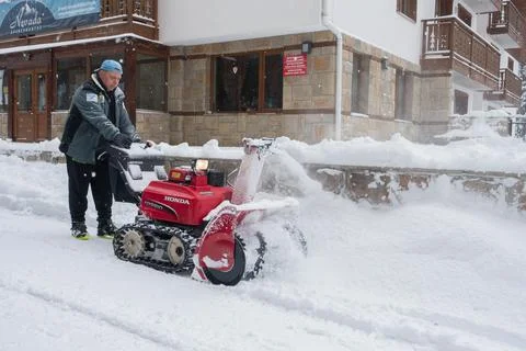 A man using an industrial petrol driven snow clearing machine clears a road  Stock Photos