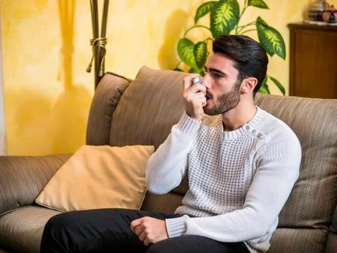 Man using inhaler on sofa Stock Photos