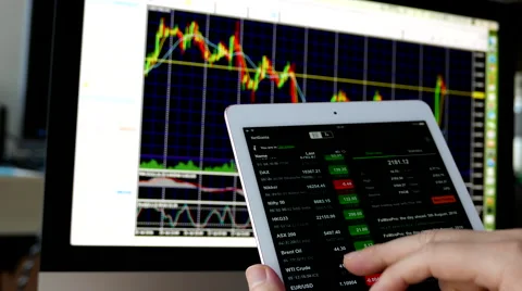 Man using ipad to check exchange rate with exchange rate chart on iMac Stock Footage 66370836