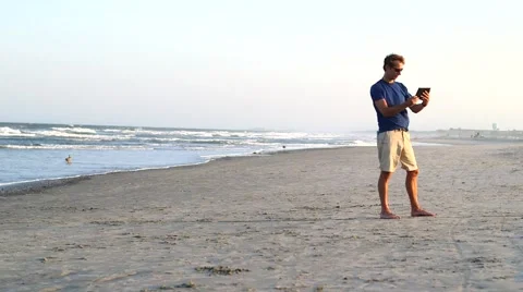 Man Using iPad/Tablet/Mobile Device at the Beach Stock Footage 63043743