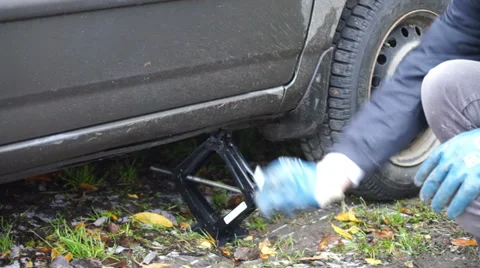 Man using a jack for putting car down Stock Footage 33212381