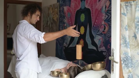 Man using a Koshi chime during sound healing therapy with tibetan singing bowls Stock Footage 213891169