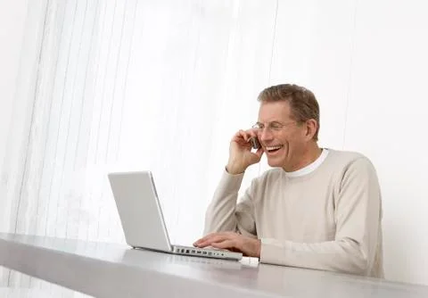 Man Using Laptop and Cell Phone Stock Photos