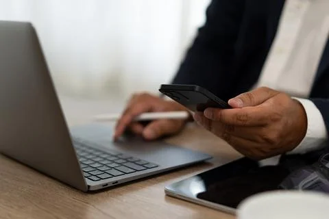 A man is using a laptop and a cell phone at the same time 写真素材