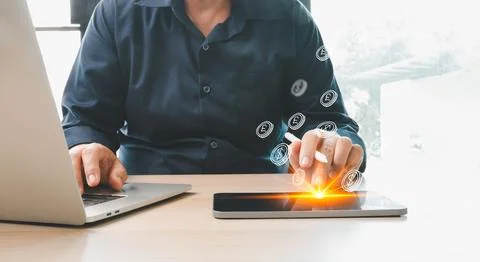Man using laptop and digital tablet with glowing virtual currency icons, re.. Foto stock