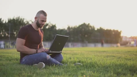Man using laptop and doing online freelance work in park Stock Footage 136370442