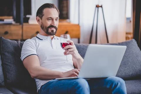 Man using laptop and drinkingwine Stock Photos