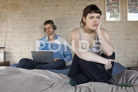 A man using a laptop and ignoring his frustrated girlfriend Stock Photos
