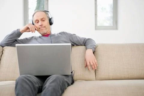 Man using a laptop and listening to music Stock Photos