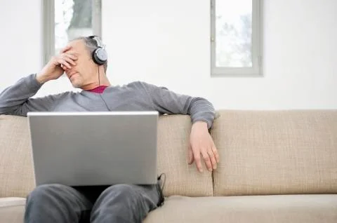 Man using a laptop and listening to music Stock Photos