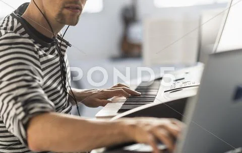 Man using laptop and synth to make music Stock Photos