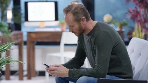 Man using laptop and texting on mobile phone in living room Stock Footage 106794922