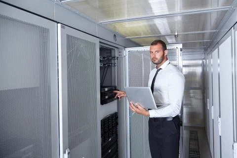 Man using laptop and working in modern server room Stock Photos