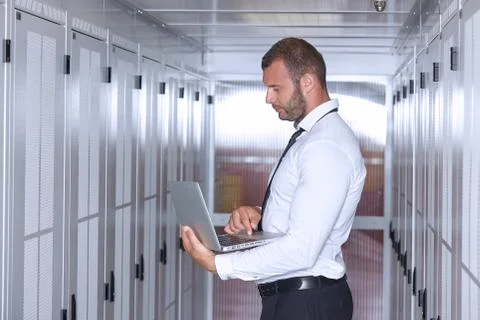Man using laptop and working in modern server room Stock Photos